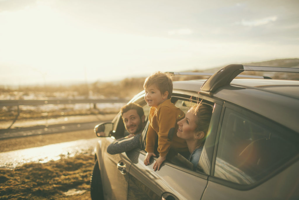 Familie på tre titter ut av bilvindu ved et vann