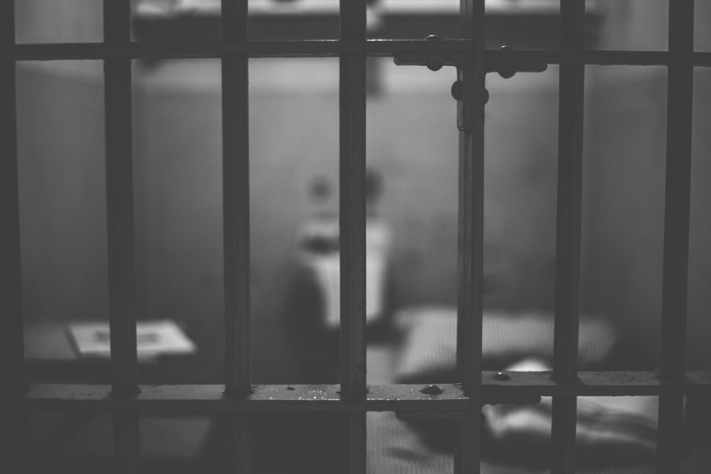 Svart-hvitt bilde av gitter foran en fengselscelle
