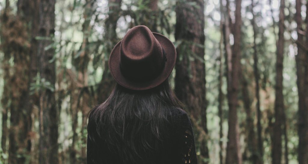 Bilde av kvinne med langt, mørkt hår og hatt, i skog